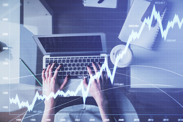 Double exposure of woman hands working on computer and forex chart hologram drawing. Top View....