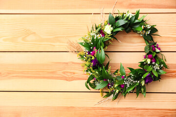 Beautiful wreath made of flowers and leaves on wooden background, top view. Space for text