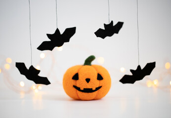 Fototapeta premium Halloween pumpkin and bats on a white background with bokeh. Pumpkin felting toy. Halloween concept.