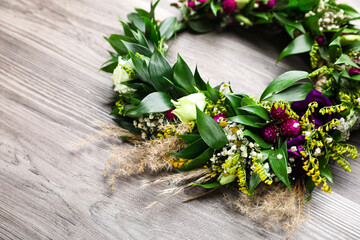 Beautiful wreath made of flowers and leaves on wooden table, closeup