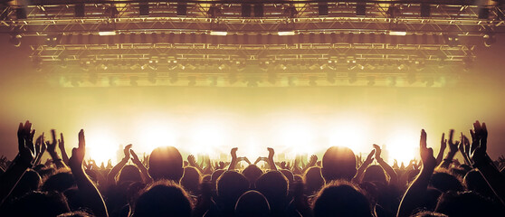Large assembly of people in front of a large stage lit in the dark.