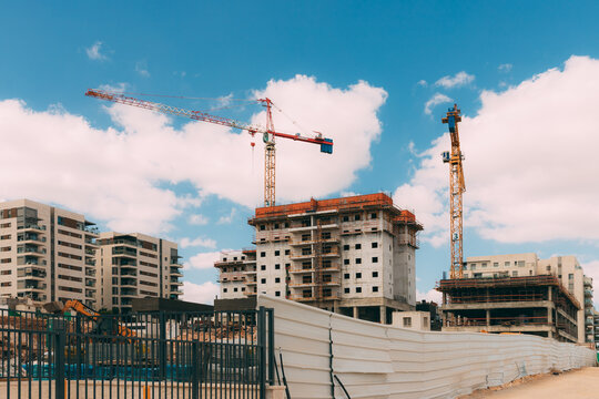 Rosh Haayin / Israel - October 4 2020: Construction site with cranes and excavator, sand on blue sky background. Modern building new houses for people. House building area in the city.