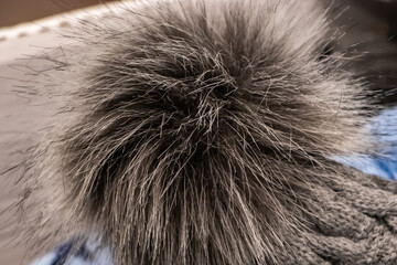 Fluffy pompon on a  knitted hat close-up.