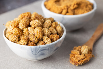 Mulberry Fruit Powder. A bowl of white dried mulberry  and dried mulberry powder on stone...