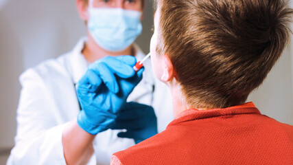 Doctor takes a cotton swab coronavirus test from child nose to analyse if postitve for covid-19.
