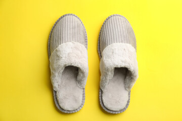Pair of soft slippers on yellow background, flat lay