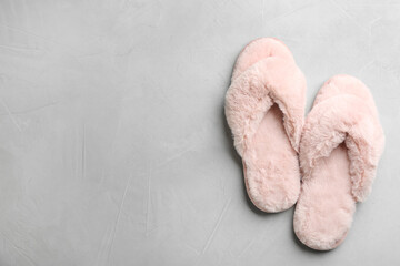Pair of soft slippers on light grey background, flat lay. Space for text