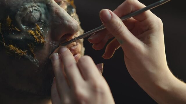 Makeup artist doing man makeup for halloween costume as zombie