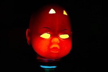 A lamp in the shape of the devil decorating a halloween party on a black background.