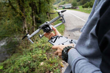Fototapeta premium Close up on drone and remote controller in hands of unknown man standing by the road in autumn day