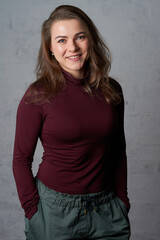 portrait of a beautiful girl in a red turtleneck near a white brick wall.