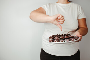 Fat woman with chocolate cookies and thumb down