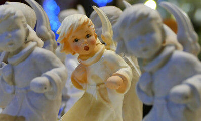 Fototapeta premium Painted ceramic figure with wings stands between unpainted figures