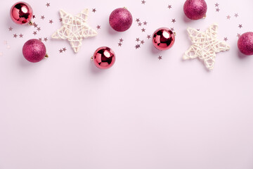 Christmas frame border of balls decoration, stars, confetti on pastel pink background. Flat lay, top view. Xmas greeting card mockup, banner design.