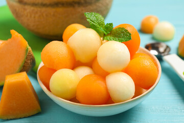 Melon balls and mint in bowl on light blue table, closeup