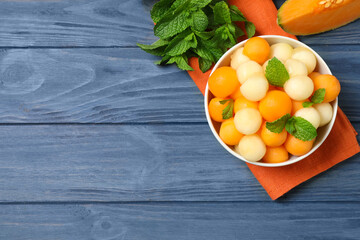 Melon balls and mint in bowl on blue wooden table, flat lay. Space for text