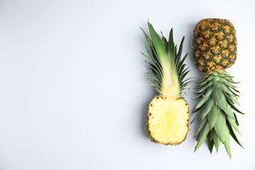 Whole and cut pineapples on white background, flat lay. Space for text