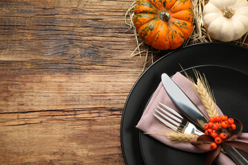 Festive table setting with pumpkins and space for text on wooden background, flat lay. Thanksgiving Day celebration