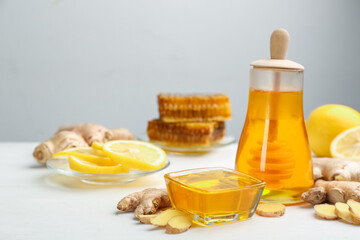 Honey, ginger and lemon on white wooden table, space for text. Natural cold remedies