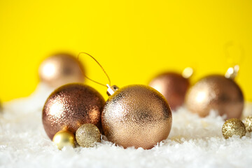 Beautiful Christmas balls on snow against yellow background. Space for text