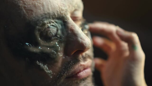 Close up of makeup artist giving actor zombie makeover before filming