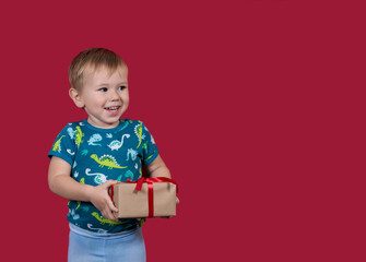 A little boy tries to unpack a New Year's gift looking aside smiling