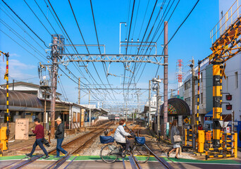 People walking or riding bicycle passing on a level crossing in the Kanegafuchi district adjacent to the Kanegafuchi station. - obrazy, fototapety, plakaty