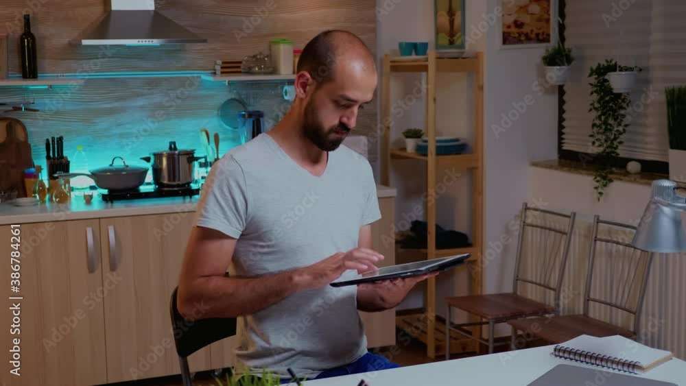 Poster businessman using tablet pc while working from home kitchen. busy focused employee using modern tech