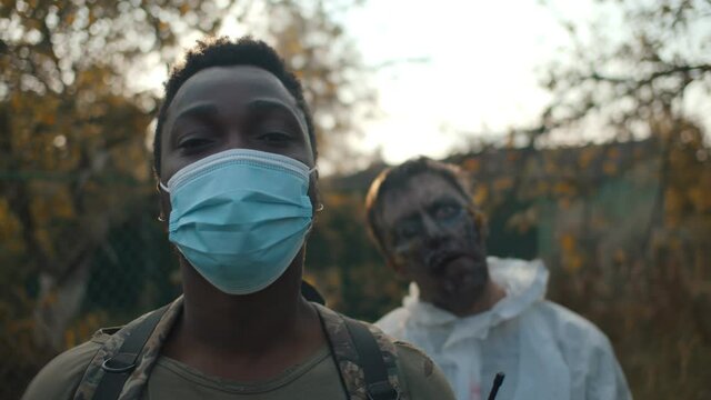 Post-apocalyptic african soldier in safety mask with zombie on background