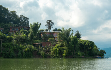 The shore of Lake Phewa in Pokhara, Nepal, from the side of Anadu Hill, with lush vegetation and residential buildings