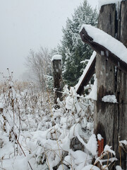 Snow covered wooden fence with barbed wire. Vertical photo.