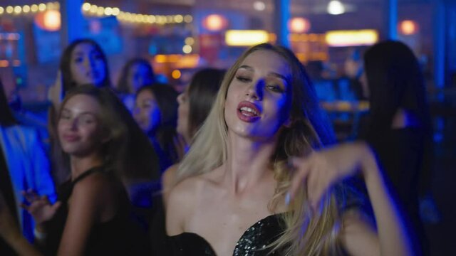 portrait of an attractive female enjoying dancing on dance field while relaxing at party with friends in nightclub
