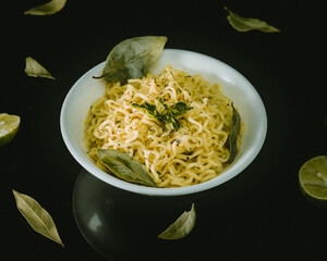 Sopa de fideos en plato blanco minimalista adornada con hojas sobre mesa negra