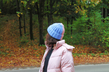 Girl in a warm 2-colored hat, autumn forest
