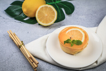 Lemon tart on a white plate decorated with lemons. Enjoy fresh baked dessert in restaurant. Closeup shot of little sweet decorative cake