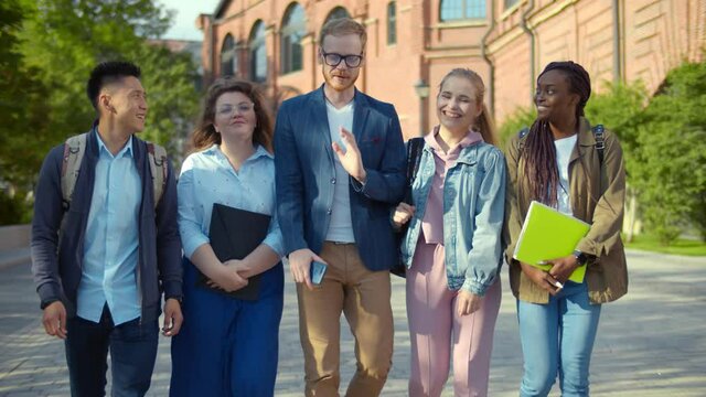 Multiethnic students walking at campus relaxing outdoors after classes