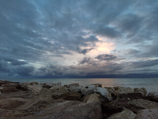 vista da scogli mare Adriatico cielo nuvole scure orizzonte rifessi luce su acqua verde