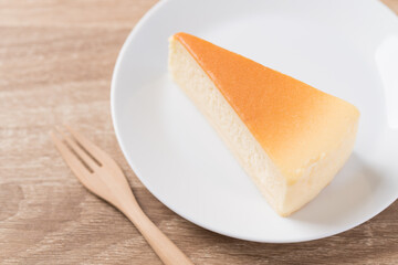 Slice of vanilla cheesecake on white plate with fork