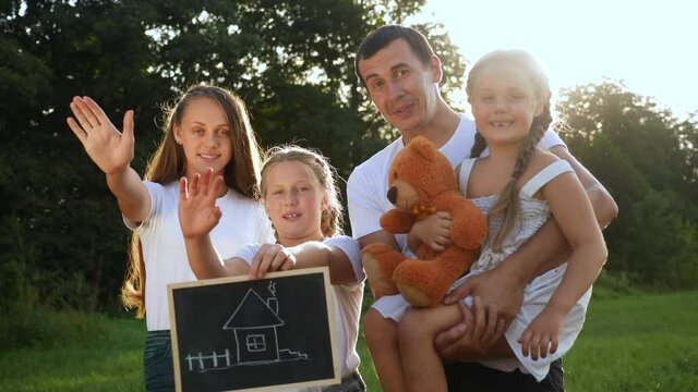 happy family in the park dreaming of their mortgage home. house concept home insurance. parent with kid in the park hold a sign symbol house. friendly happy lifestyle family concept