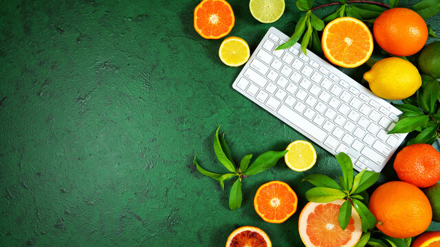 Health food theme background workspace with citrus fruit on dark green textured background. Top view blog hero header creative composition flat lay with negative copy space.