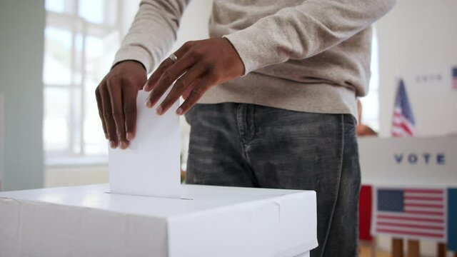 Unrecognizable african-american man putting his vote in the ballot box, usa elections and coronavirus.