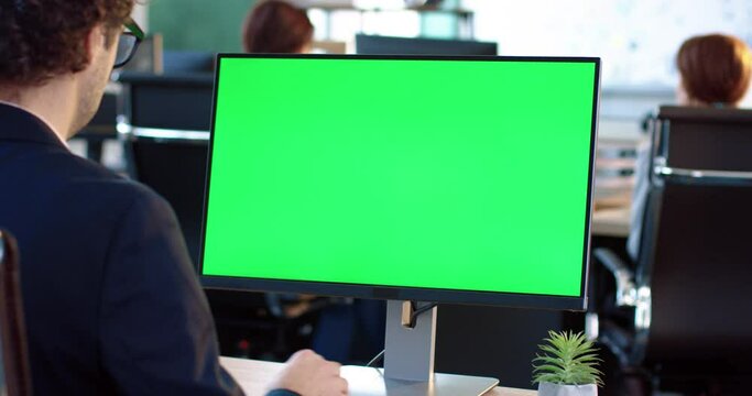 Close up of monitor in office. Green screen. Employee working at computer sitting at desk. View from back.