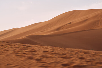 Fototapeta na wymiar Sand dunes in the desert with orang color in Xinjian, China.