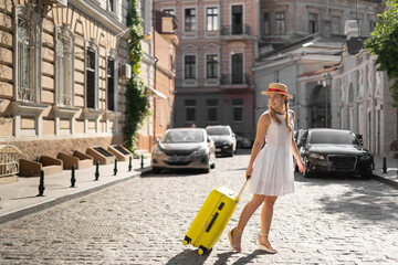 Woman traveler tourist walks with luggage around the city.