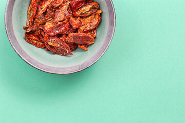 Sun dried tomatoes slices with Italian herbs and spices on blue colored background. Homemade dehydrated vegetable.