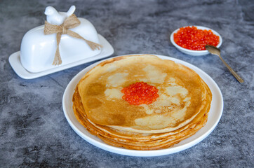 Traditional Russian thin pancakes (crepes) with red caviar on a blue background.	