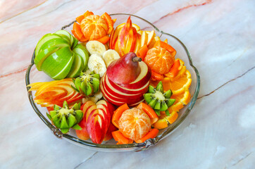 Pear, apples, oranges, tangerines, bananas and kiwi on a glass plate. Fresh mix of fruits.