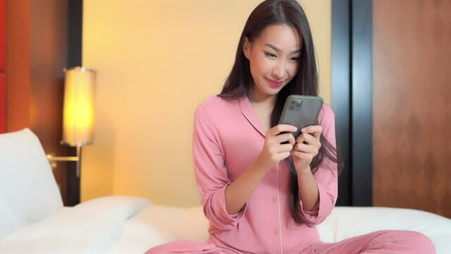 Adult Woman in Pajamas Sitting on Bed Using Smartphone, Texting SLOMO