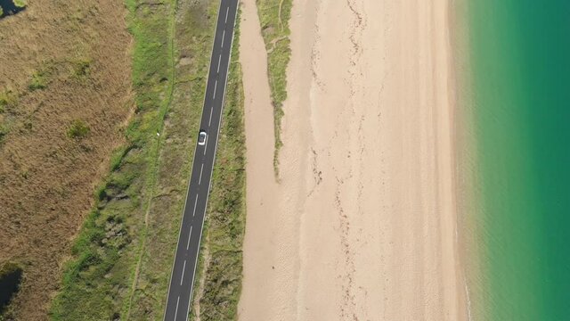 Birds eye view of car driving along scenic highway by ocean