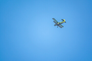 Fototapeta na wymiar Retro green biplane plane in the blue sky